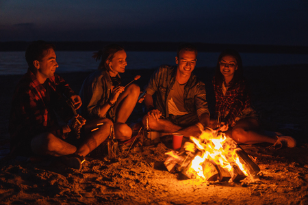 young friends have picnic with bonfire on the beachの写真素材