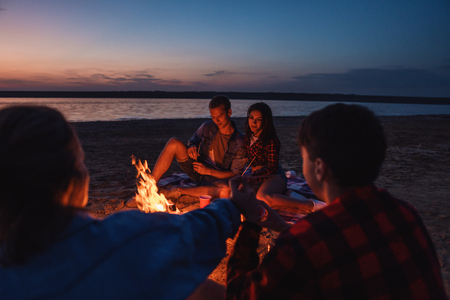 young friends have picnic with bonfire on the beachの写真素材