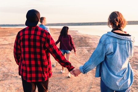 friends on beach together walking during sunsetの写真素材