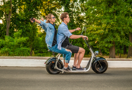 Lovely young couple driving electric bike during summerの写真素材