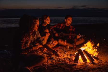 young friends have picnic with bonfire on the beachの写真素材