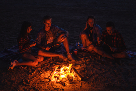 young friends have picnic with bonfire on the beachの写真素材