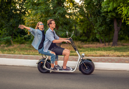 Lovely young couple driving electric bike during summerの写真素材