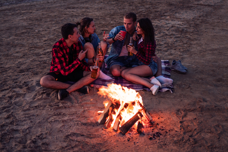 young friends have picnic with bonfire on the beachの写真素材