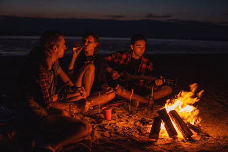 young friends have picnic with bonfire on the beachの写真素材
