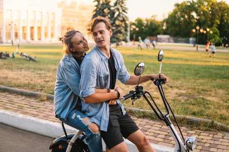 Lovely young couple driving electric bike during summerの写真素材