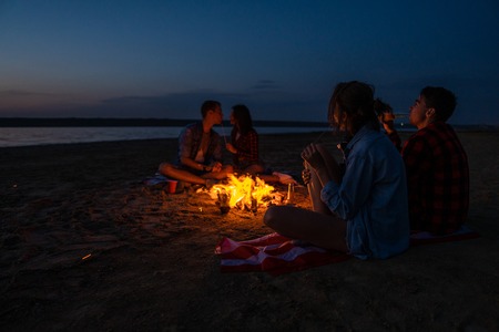 young friends have picnic with bonfire on the beachの写真素材