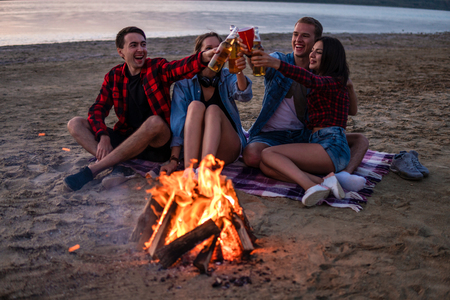 young friends have picnic with bonfire on the beachの写真素材