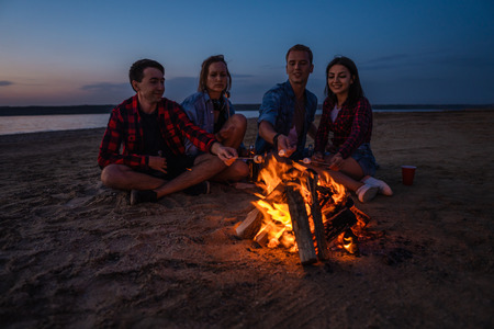 young friends have picnic with bonfire on the beachの写真素材