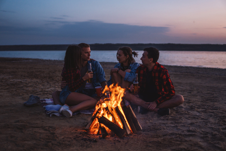 young friends have picnic with bonfire on the beachの写真素材