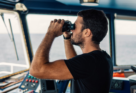 Navigational officer lookout on navigation watch looking through binocularsの写真素材