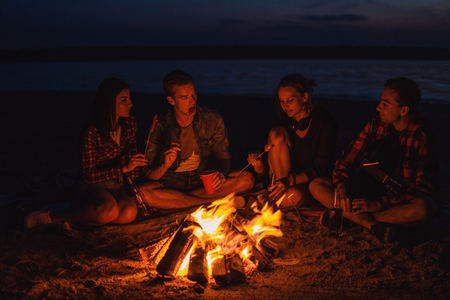 young friends have picnic with bonfire on the beachの写真素材