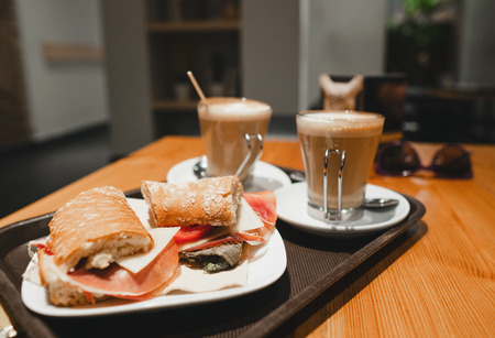 breakfest snack - coffee latte and bocadillo sandwich on table in one cafeの写真素材