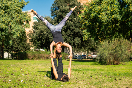 Beautiful couple practicing acro yoga in the morningの写真素材