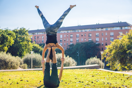 Beautiful couple practicing acro yoga in the morningの写真素材