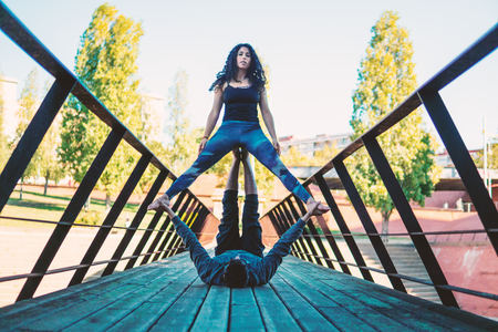 Beautiful couple practicing acro yoga in the morningの写真素材