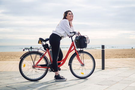 Woman riding bicycle along beach sand at summer timeの写真素材