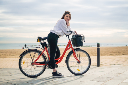 Woman riding bicycle along beach sand at summer timeの写真素材