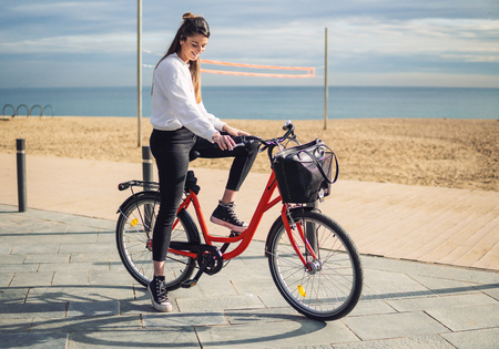Woman riding bicycle along beach sand at summer timeの写真素材