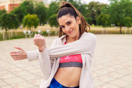 Runner fit woman warming up before sport training in the park