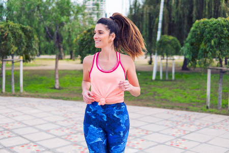 Young beautiful fit woman is running in the parkの写真素材