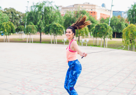 Fit beautiful woman with jumping rope in a parkの写真素材