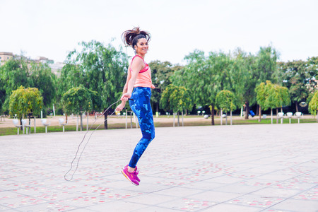 Fit beautiful woman with jumping rope in a parkの写真素材