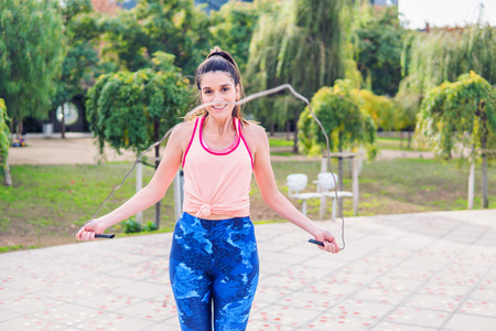 Fit beautiful woman with jumping rope in a parkの写真素材