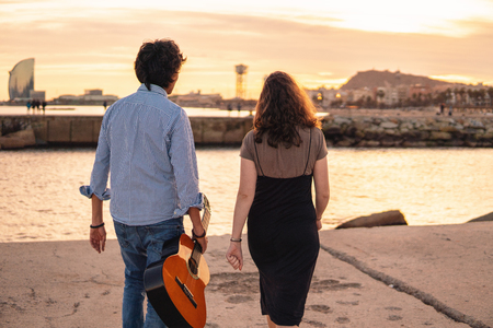 couple of musicians date and walk with guitar near the beachの写真素材