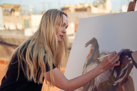 Young woman paint artist drawing at home roofの写真素材