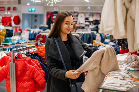 Customer woman choosing baby clothes in the shopの写真素材