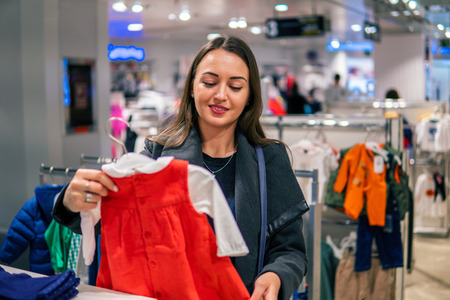 Customer woman choosing baby clothes in the shopの写真素材
