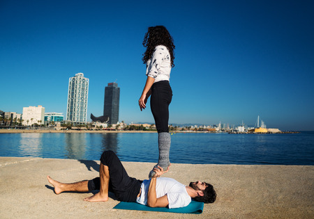 Beautiful couple practicing acro yoga in the morningの写真素材