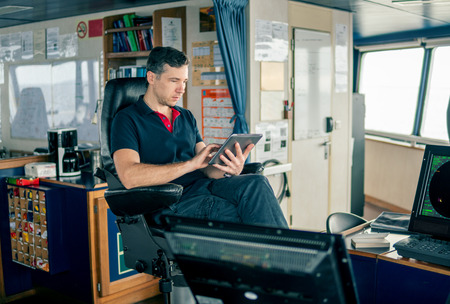 chief officer on navigation bridge watching digital tablet.の写真素材
