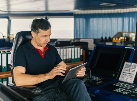 chief officer on navigation bridge watching digital tablet.の写真素材