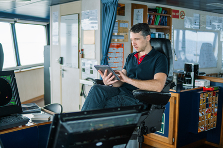 chief officer on navigation bridge watching digital tablet.の写真素材