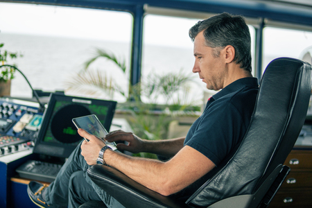 chief officer on navigation bridge watching digital tablet.の写真素材