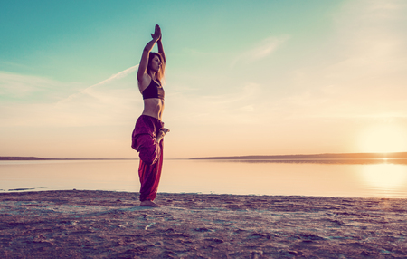 yoga woman on the beach at sunset.の写真素材