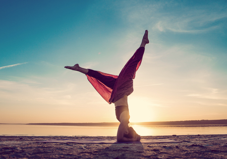 Silhouette yoga woman on the beach at sunset.の写真素材