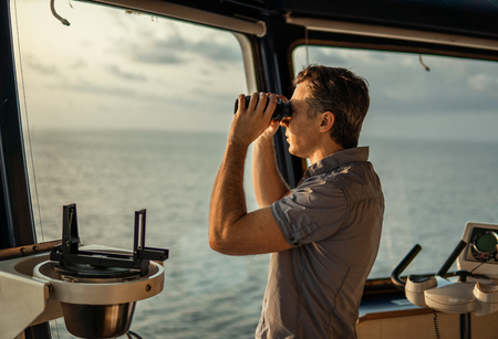 Navigational officer lookout on navigation watch with binocularsの写真素材