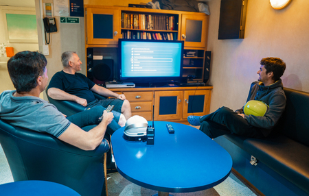Happy team of ship officers watch TV onboard of vesselの写真素材