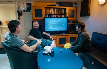 Happy team of ship officers watch TV onboard of vesselの写真素材