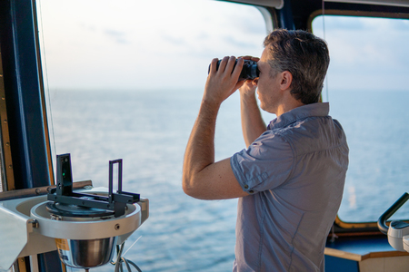 Navigational officer lookout on navigation watch with binocularsの写真素材