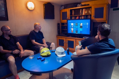 Happy team of ship officers watch TV onboard of vesselの写真素材