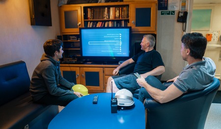 Happy team of ship officers watch TV onboard of vesselの写真素材