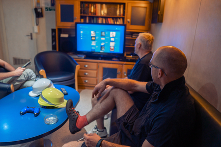 Happy team of ship officers watch TV onboard of vesselの写真素材