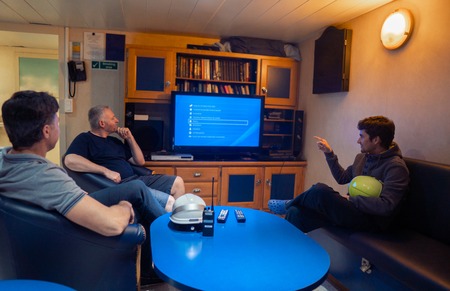 Happy team of ship officers watch TV onboard of vesselの写真素材