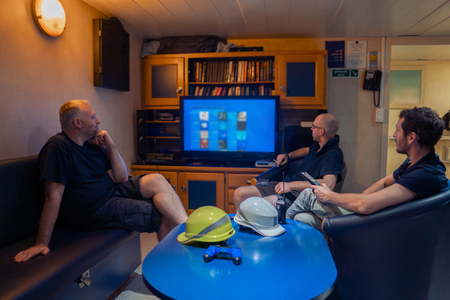 Happy team of ship officers watch TV onboard of vesselの写真素材