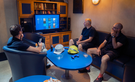 Happy team of ship officers watch TV onboard of vesselの写真素材