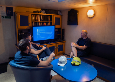 Happy team of ship officers watch TV onboard of vesselの写真素材